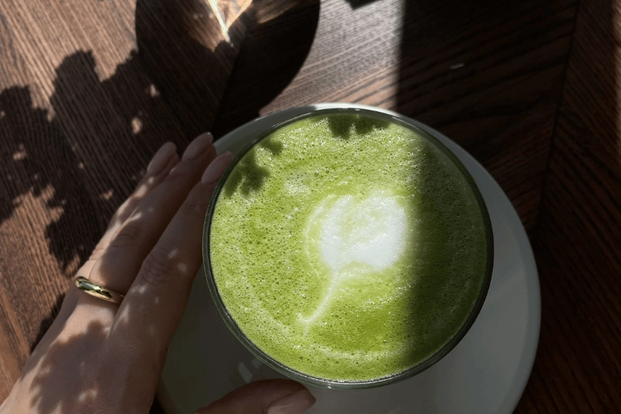 Enjoying a green matcha latte with latte art in a mug